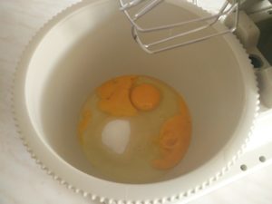 The sugar and 3 eggs in the mixing bowl
