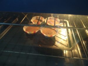 Overflow cake mix in cupcake cases, in the oven