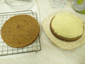 A cake half with icing on, and the other half on a wire rack