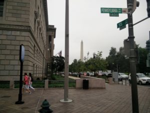 A sign showing "Pennsylvania Avenue" and the Washington Monument in the background
