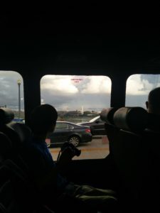 The Washington Monument from afar, with buildings, cars and a bridge in the way