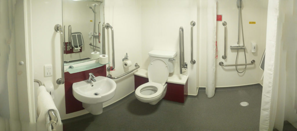 A panoramic view of the hotel bathroom, showing no shower tray, but a wet room